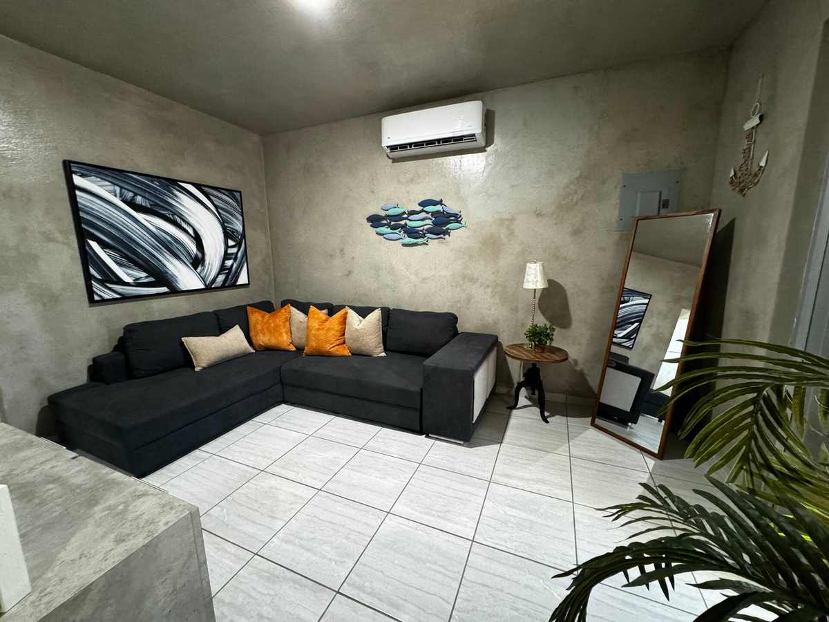 Sala con sofá gris oscuro y cojines anaranjados